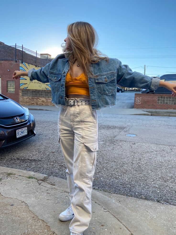 Full length outdoor portrait of cream coffee-blonde color haired girl wearing crop denim with top and cargo pants. 